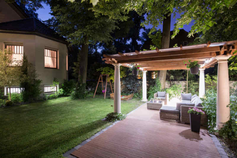 Backyard living space with a covered pergola accented with low voltage landscape lighting