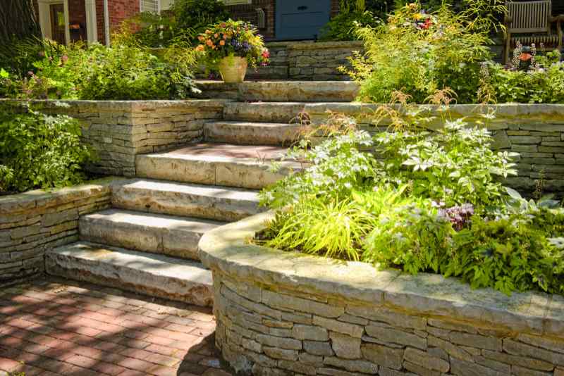 Natural stone landscaping and hardscape in home garden with stairs and retaining walls