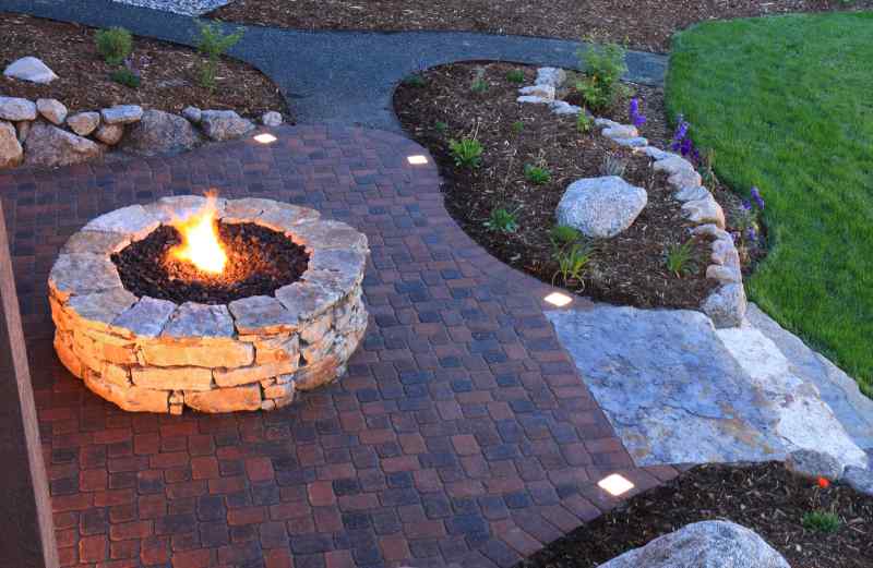Overhead view of fire pit and backyard patio landscape pavers at dusk. Paver patio has built in lighted pavers.