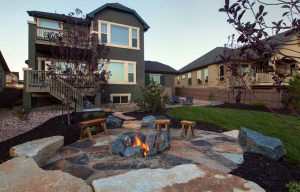 Fully landscaped backyard with a beautiful fire pit and stone patio by Heartland landscape services, Sunrise Beach MO.