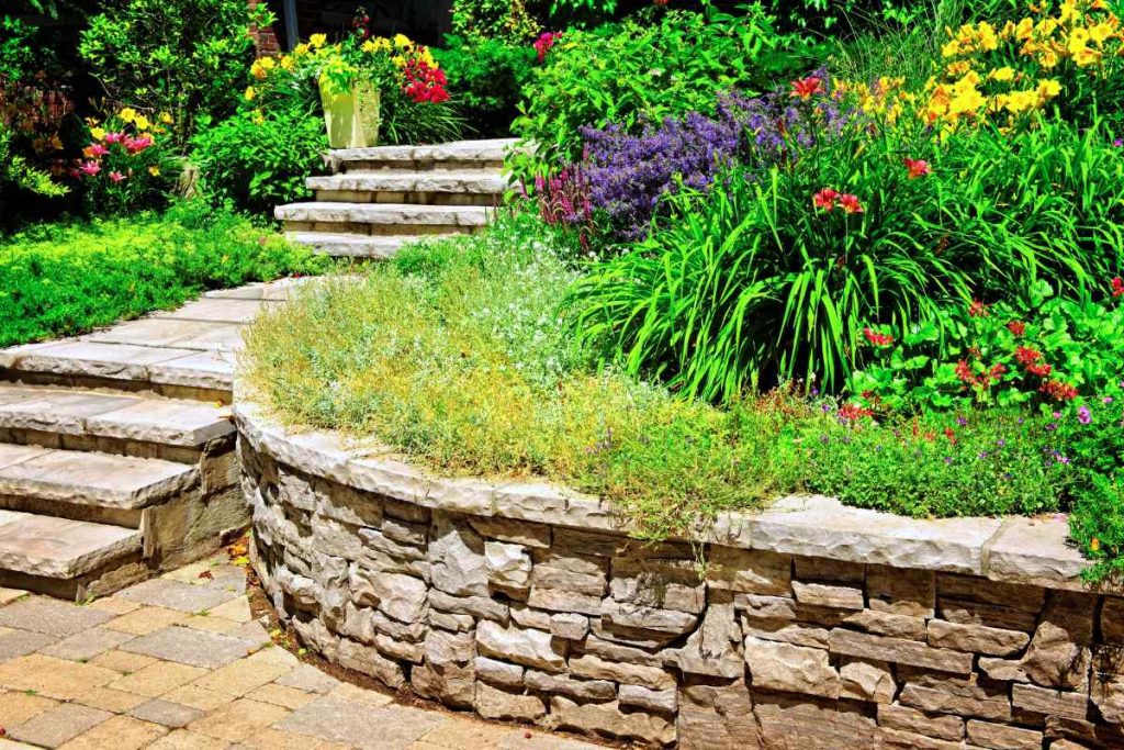 A beautiful landscape design in Jefferson City, MO with hardscaped retaining walls, stone steps, and flowers